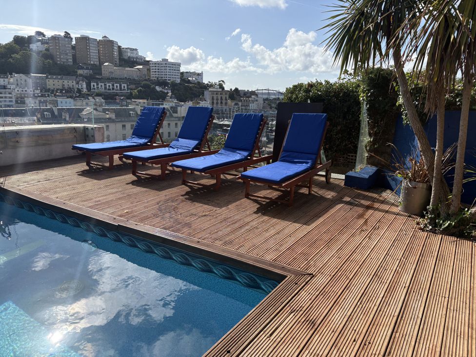An outdoor space with sun loungers and a pool at Delmonte Lodge in Torquay