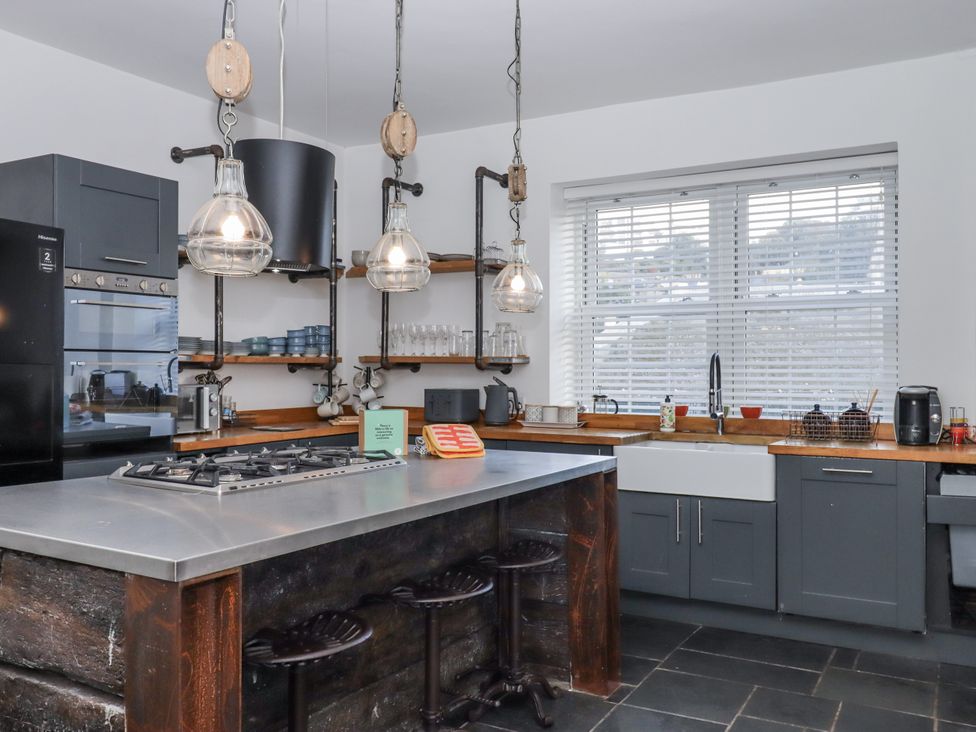 A kitchen with a cooking range and stools at Delmonte Lodge in Torquay