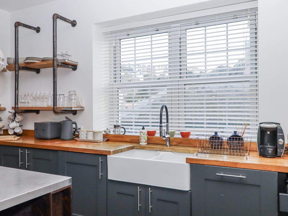 A kitchen featuring a sink, shelves with glassware, and a kettle at Delmonte Lodge in Torquay