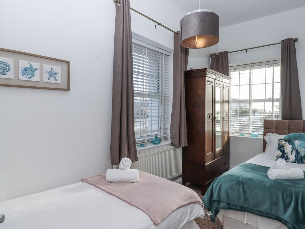A bedroom with two beds and a wardrobe at Delmonte Lodge in Torquay