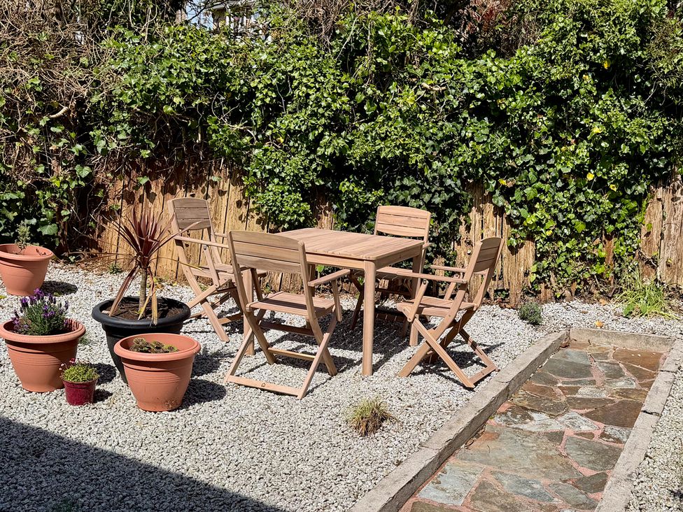 A garden with a table and chairs surrounded by potted plants at Falmouth Bay 1, Falmouth