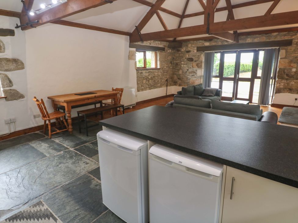 An open plan living area with a dining table and chairs at The Shippen in Rosudgeon