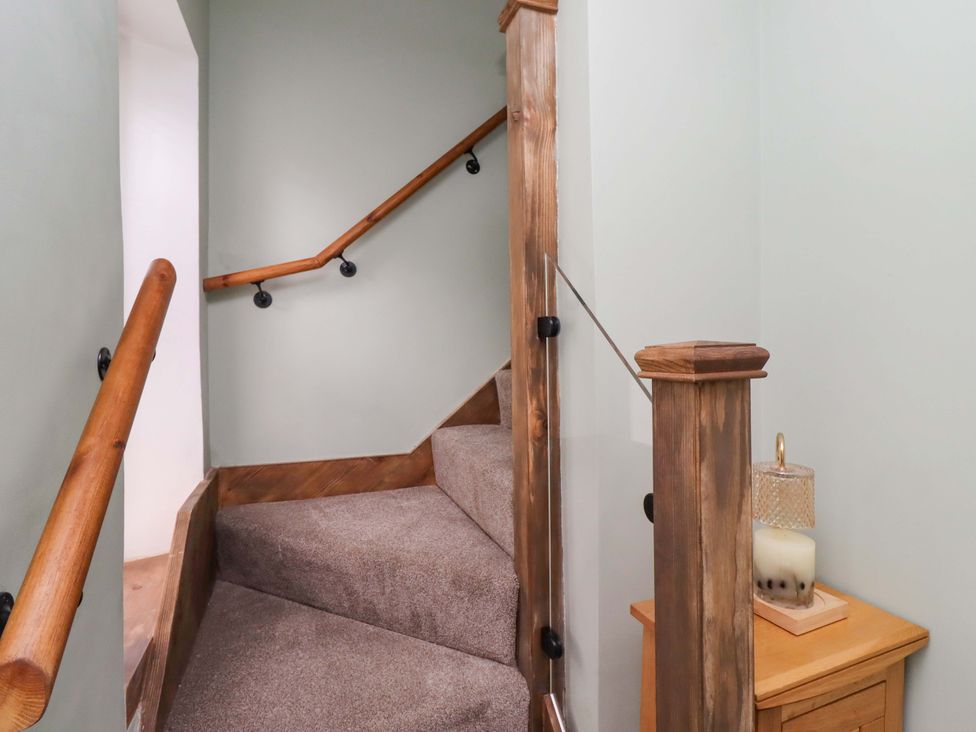 A staircase with wooden handrail and candle holder at The Lodge in Powburn