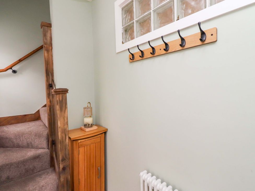 A hallway with hooks and a staircase at The Lodge in Powburn