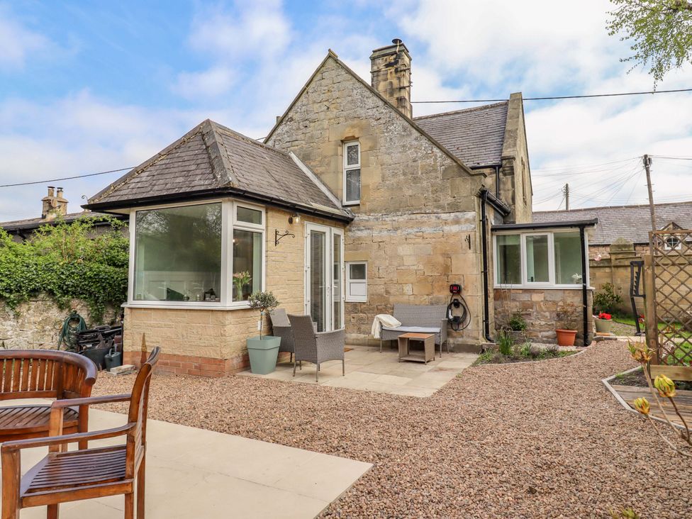 A garden area with chairs and a house at The Lodge in Powburn
