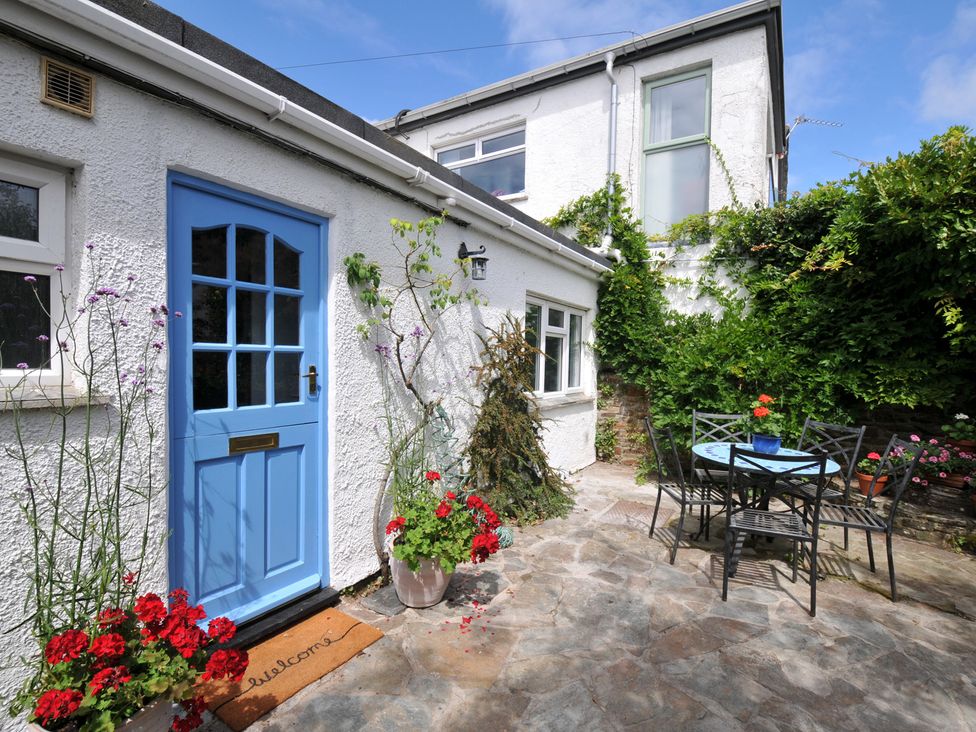 A garden with a blue door and a table with chairs at 2 Porthilly Cottages Rock