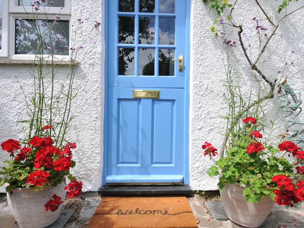 An outdoor entrance with a blue door and flower pots at 2 Porthilly Cottages in Rock