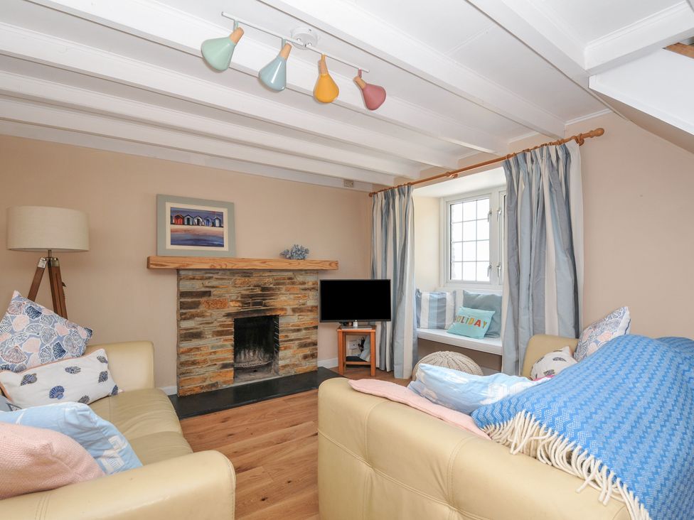 A living room with a fireplace and sofa at 2 Porthilly Cottages in Rock