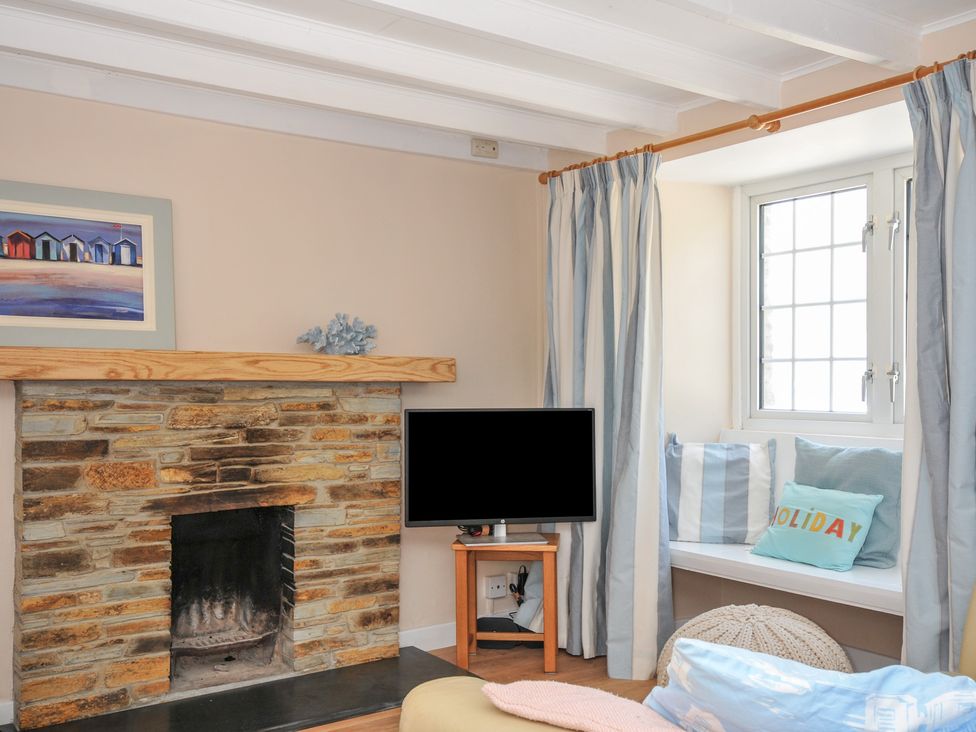 A snug with a fireplace and television at 2 Porthilly Cottages in Rock