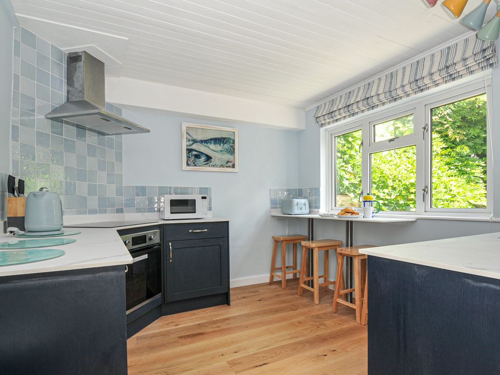 A kitchen with countertop, stools, and appliances at 2 Porthilly Cottages in Rock