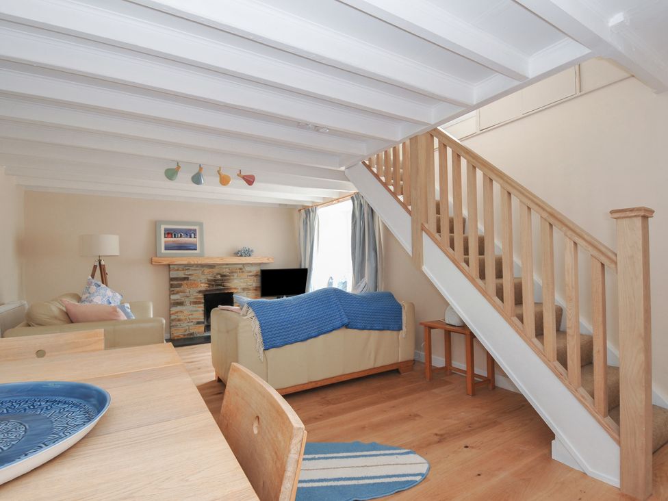 A living room with a sofa and dining table at 2 Porthilly Cottages Rock