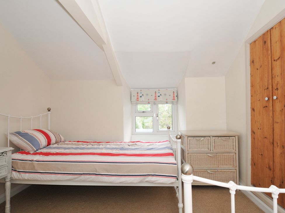 A bedroom with a bed and chest of drawers at 2 Porthilly Cottages Rock