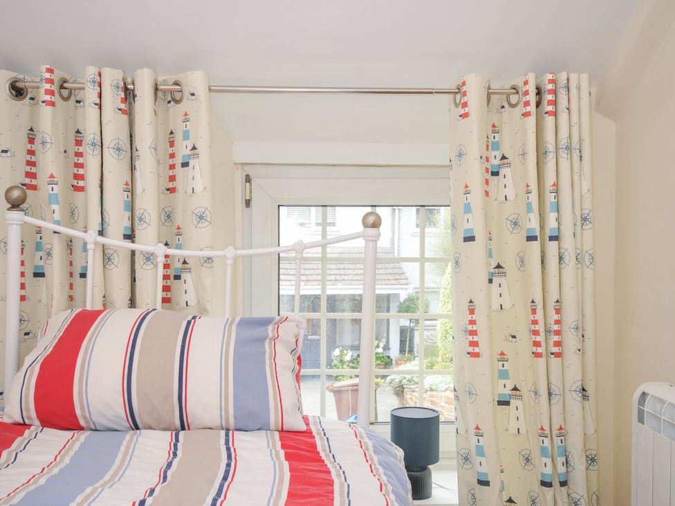 A bedroom with a bed and curtains at 2 Porthilly Cottages in Rock