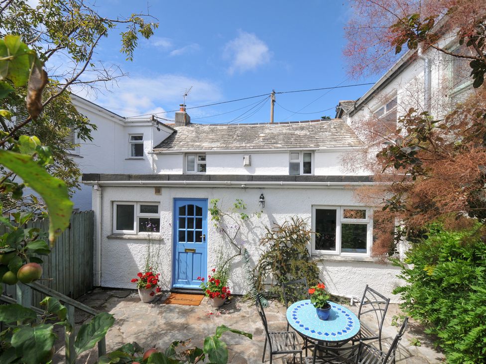 A garden with a house and seating area at 2 Porthilly Cottages in Rock