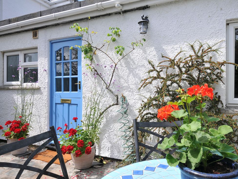 An outdoor area with a blue door, flower pots and a table at 2 Porthilly Cottages, Rock