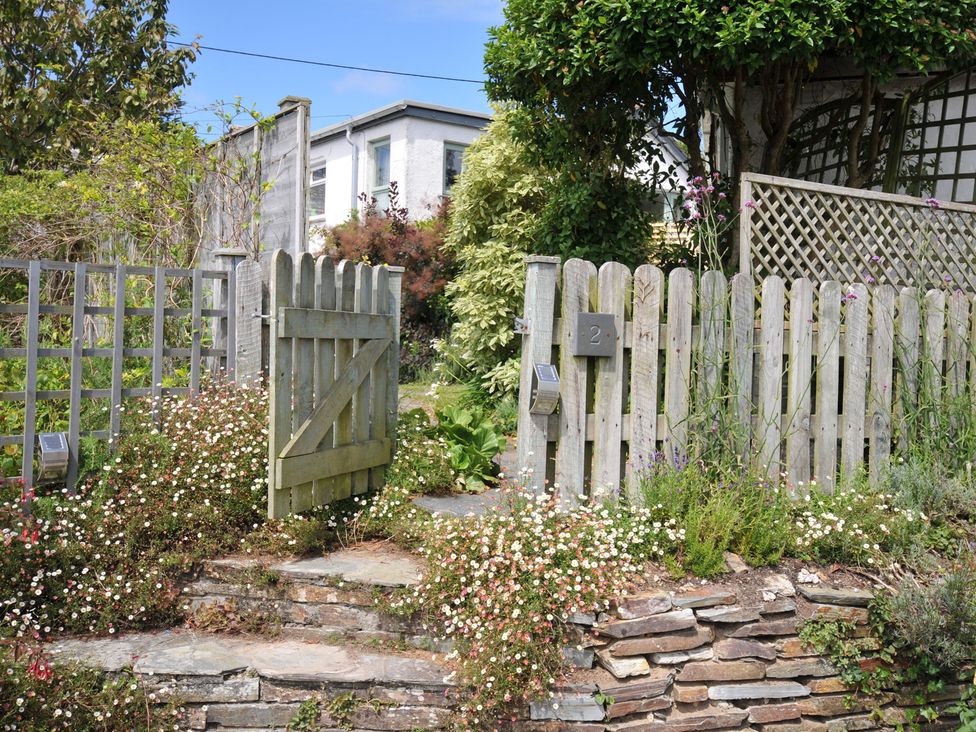 A garden gate and path with flowers at 2 Porthilly Cottages in Rock