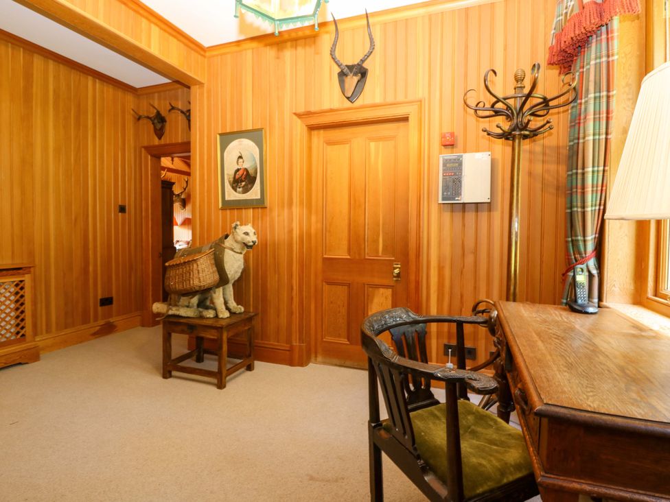 A hallway with wooden walls and a chair at Creag Bhalg near Mar Lodge Braemar