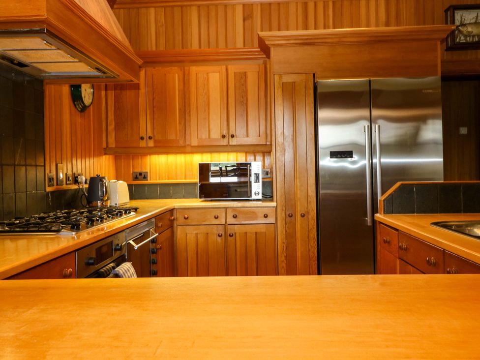 A kitchen with wooden cabinets and appliances at Creag Bhalg near Braemar
