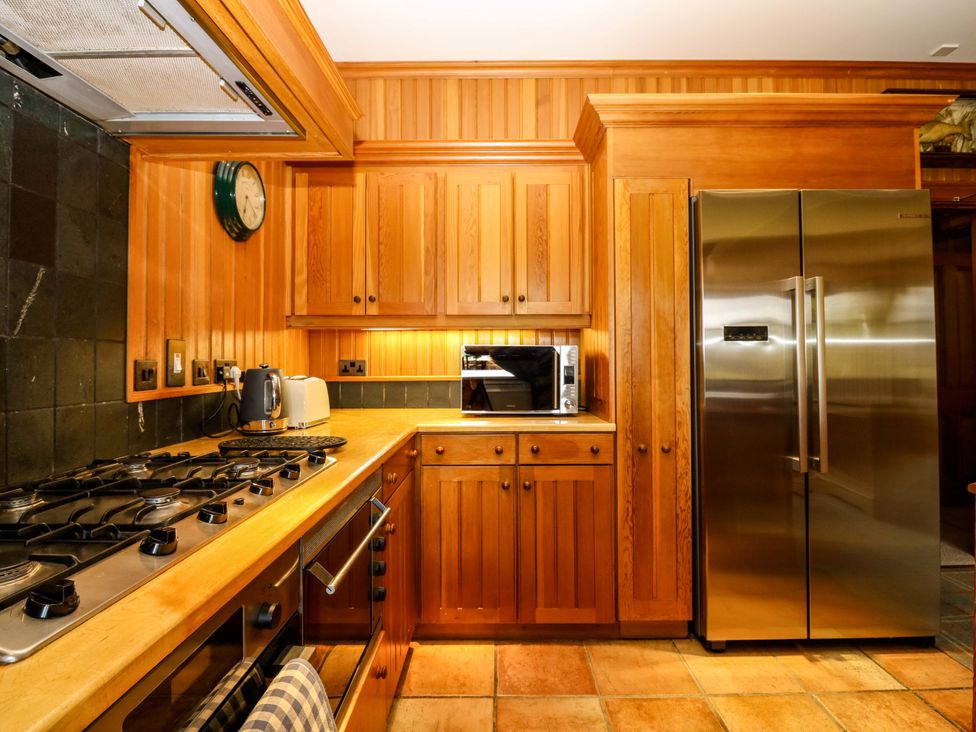 A kitchen with wooden cabinets and stainless steel refrigerator at Creag Bhalg near Mar Lodge near Braemar