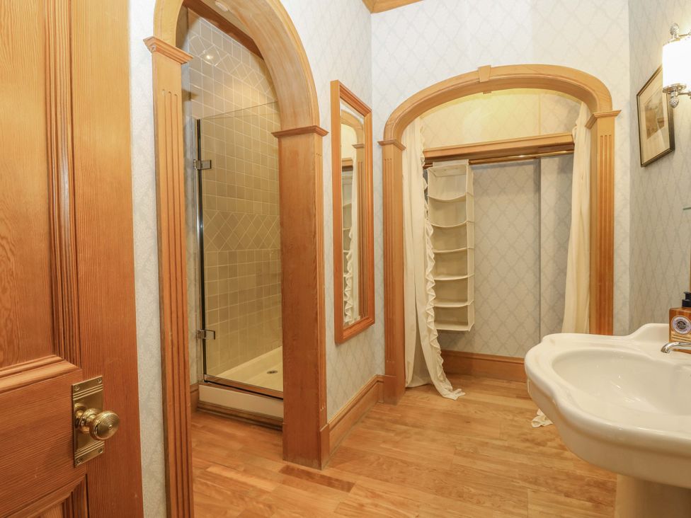 A bathroom with a shower, sink, and closet at Creag Bhalg near Mar Lodge
