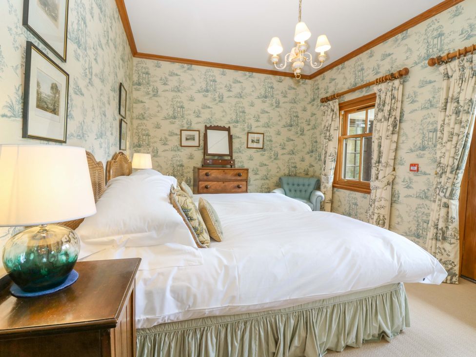 A bedroom with two beds and a chair at Creag Bhalg near Mar Lodge Braemar