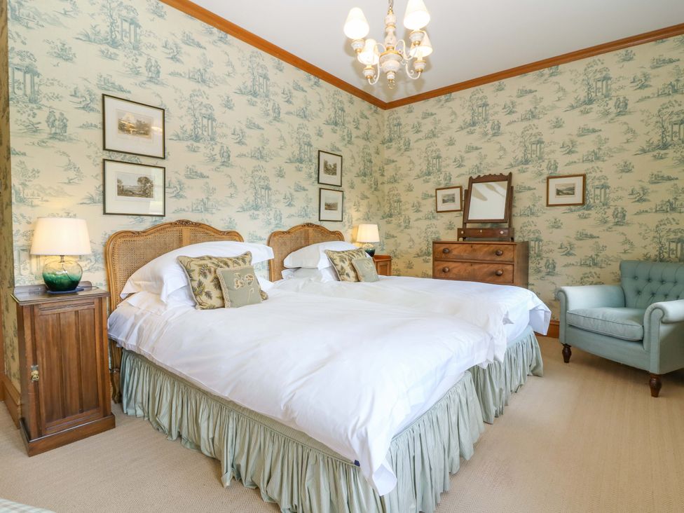 A bedroom with two beds and a chair at Creag Bhalg, Mar Lodge near Braemar