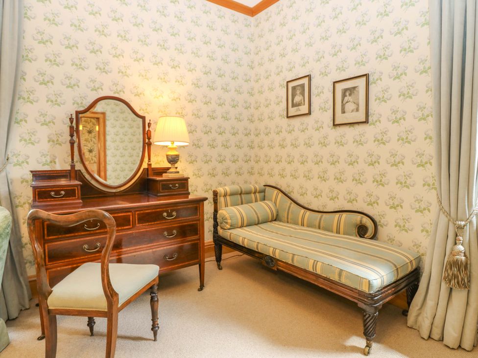 A bedroom with a dressing table and chaise lounge at Creag Bhalg Mar Lodge near Braemar