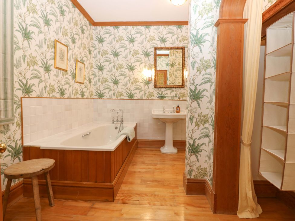 A bathroom with a bath tub, sink, and shelf at Creag Bhalg near Braemar