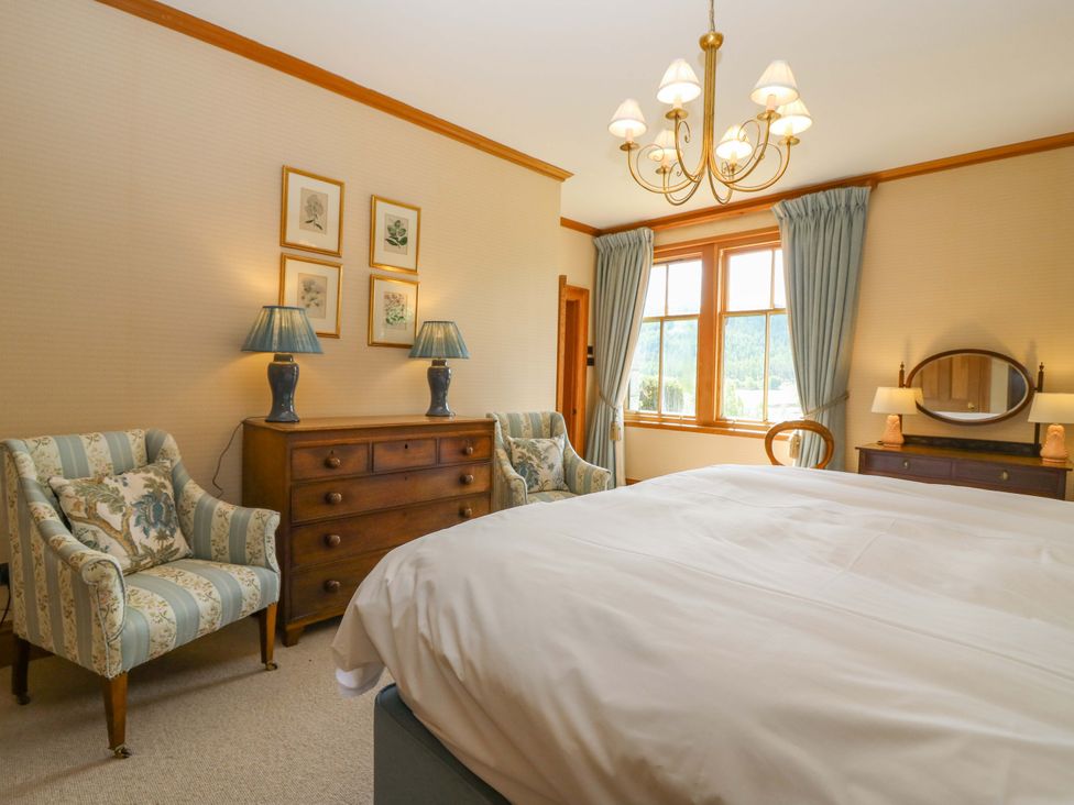 A bedroom with a bed, dresser, and armchairs at Creag Bhalg Mar Lodge near Braemar
