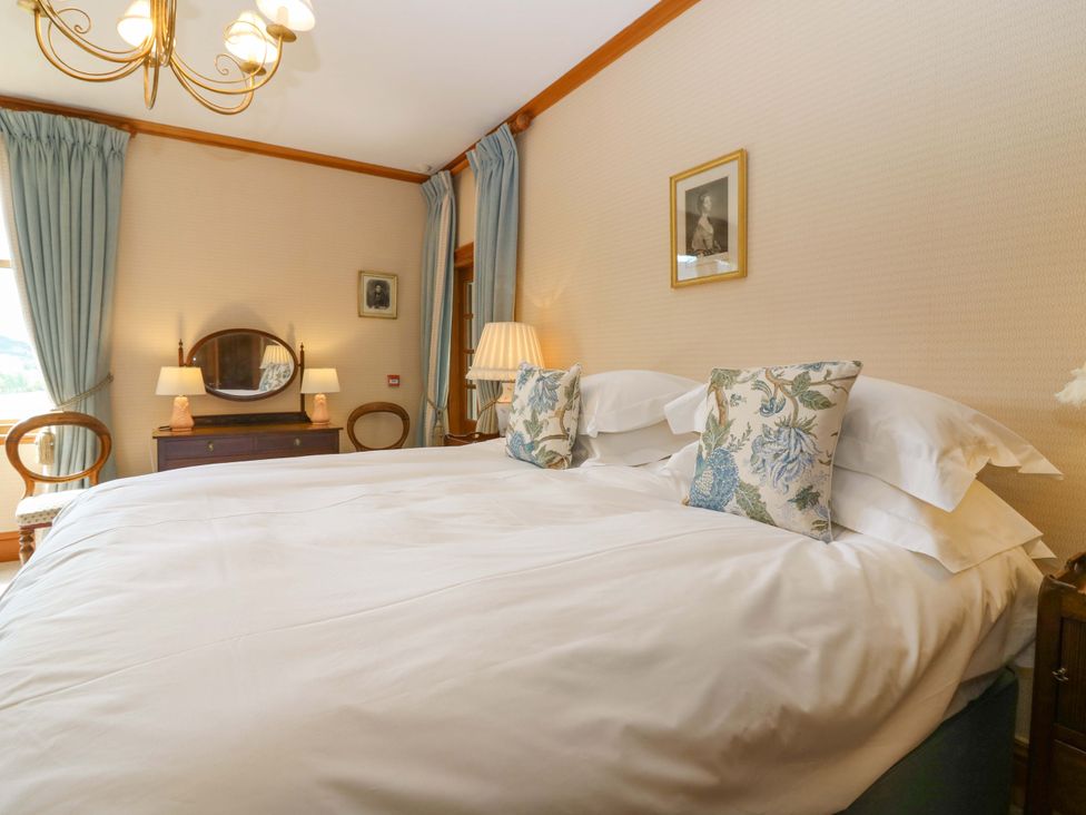 A bedroom with a large bed and a nightstand at Creag Bhalg near Mar Lodge Braemar