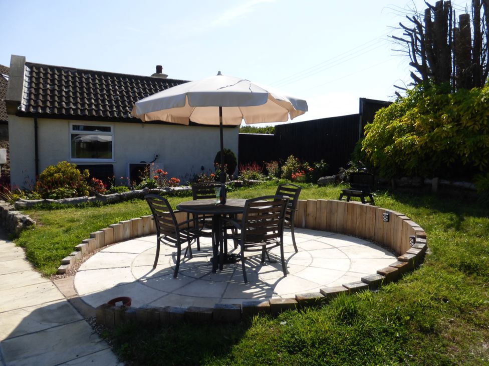 A garden with a table and chairs under an umbrella at Meadow Cottage in Staintondale near Cloughton