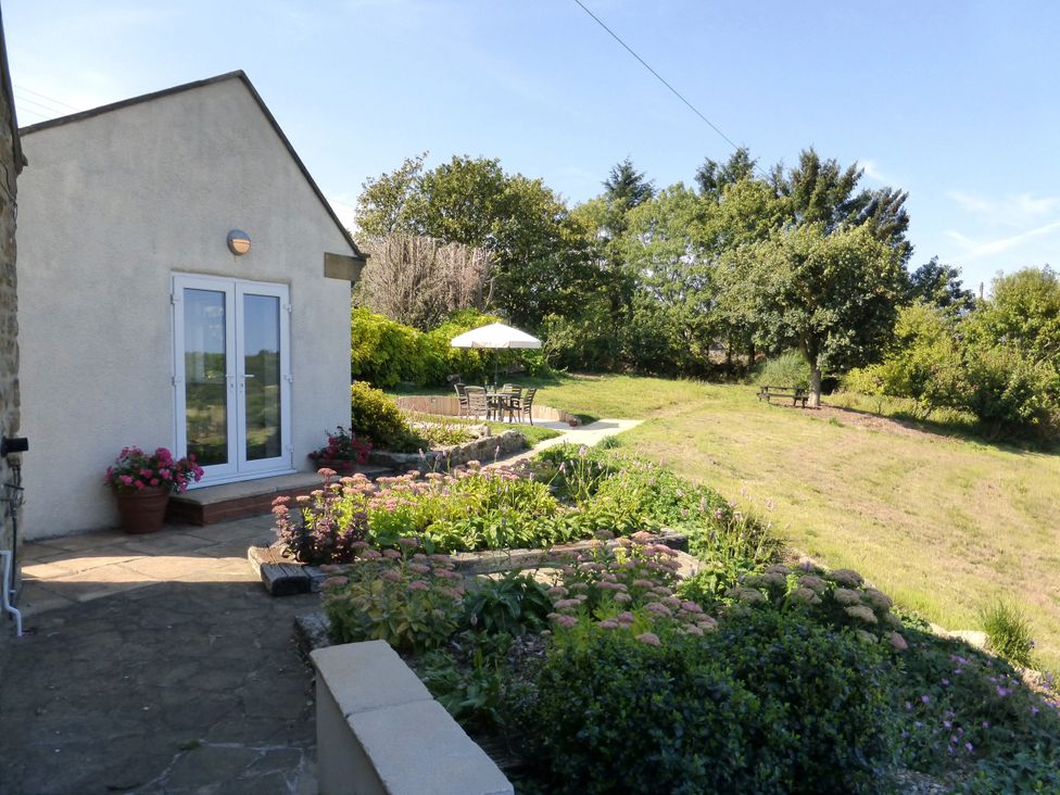 A garden with flowers, a table, and chairs at Meadow Cottage in Staintondale near Cloughton