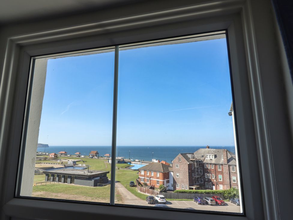 A coastal view from a window showing buildings a parking lot green lawn and the sea at Mamoir's Place in Whitby