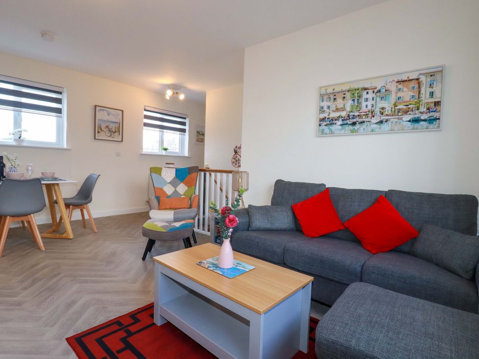 A living room with a sofa and dining area at 1 Vetch Avenue St Austell