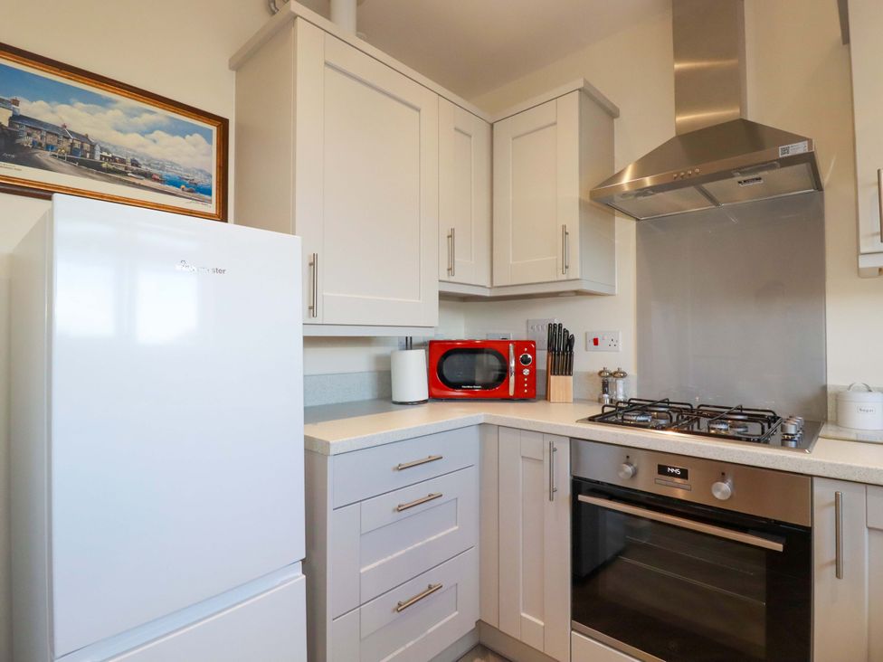 A kitchen with a fridge, stove, and microwave at 1 Vetch Avenue, St Austell