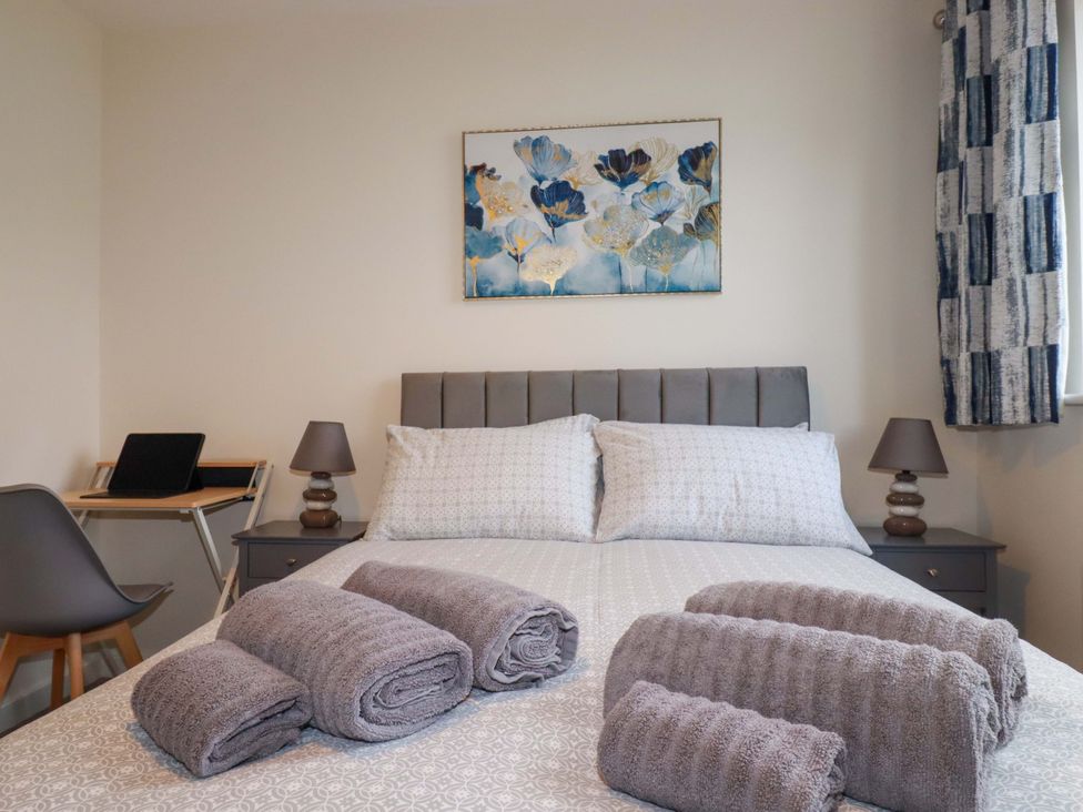 A bedroom with a bed, towels on it, and a desk at 1 Vetch Avenue in St Austell