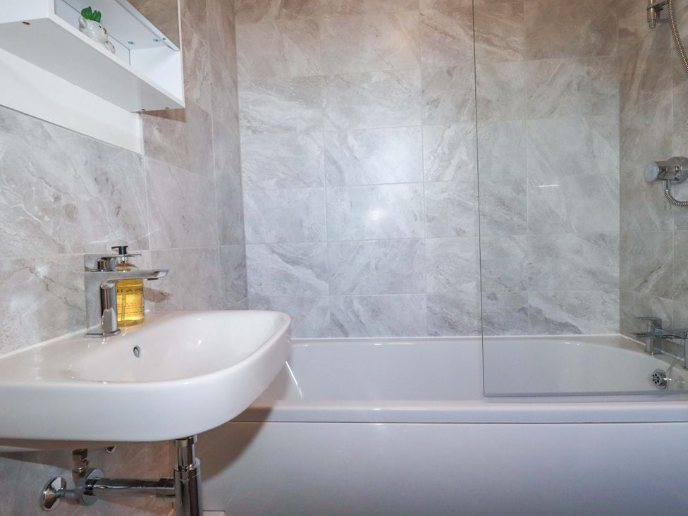 A bathroom with a bath tub and sink at 1 Vetch Avenue in St Austell