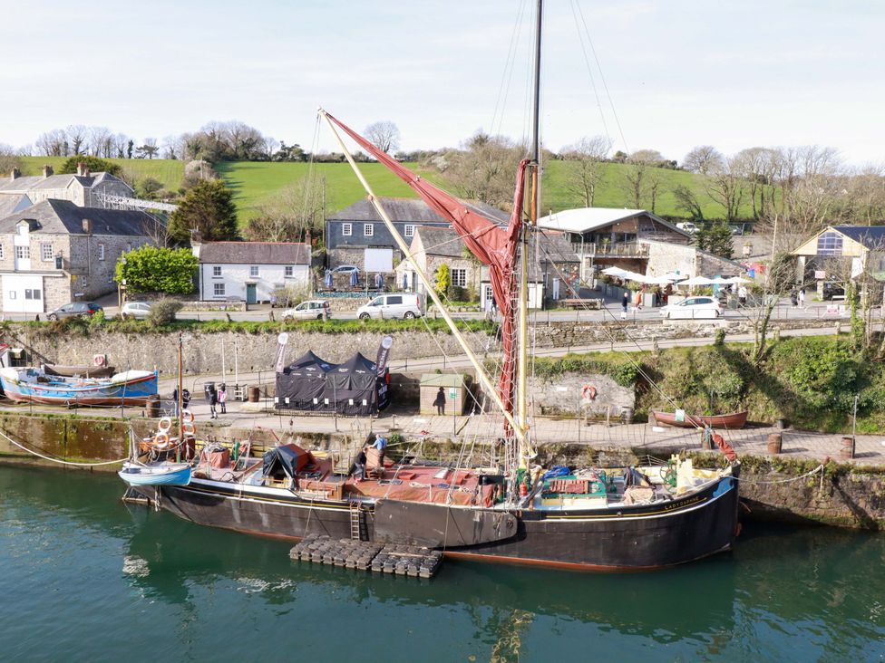 A boat docked at a waterfront with buildings and trees in the background at 1 Vetch Avenue St Austell