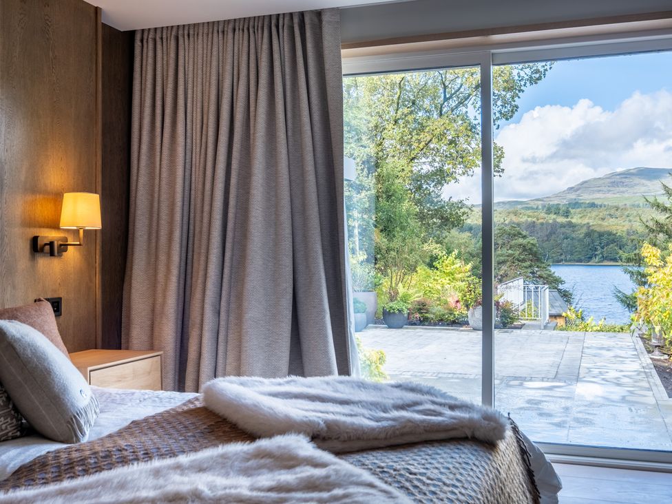 A bedroom with a bed and window overlooking a lake at Deer Close in Coniston