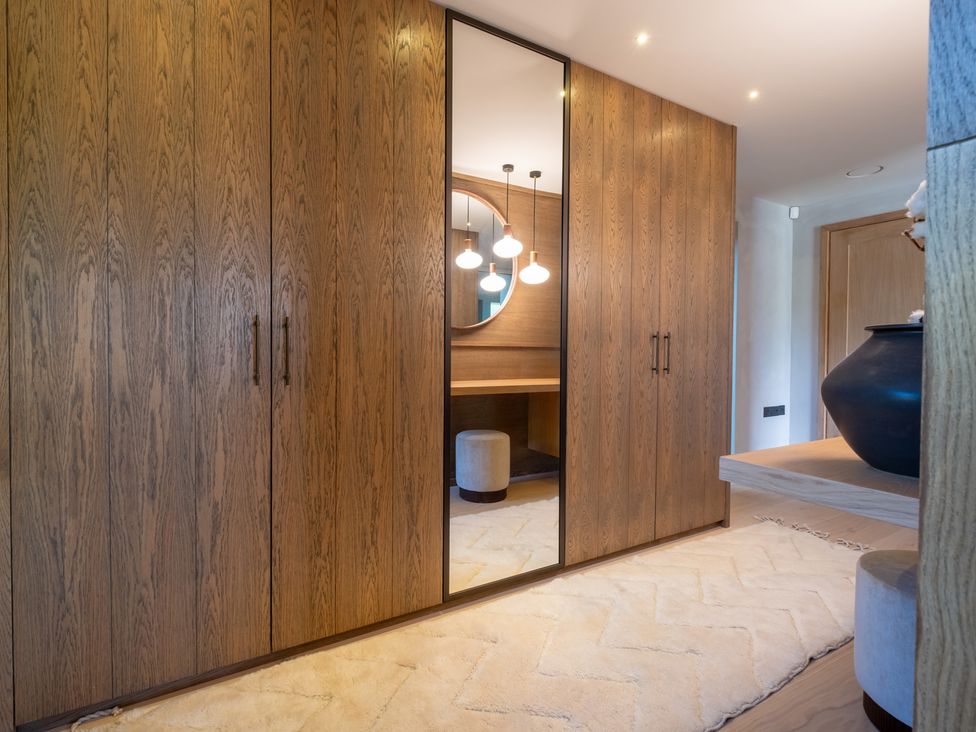 A dressing room with a wardrobe and mirror at Deer Close in Coniston