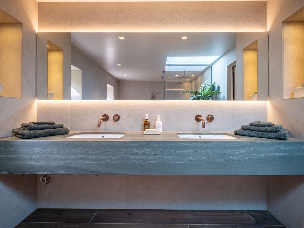 A bathroom with a double sink and mirrors at Deer Close in Coniston