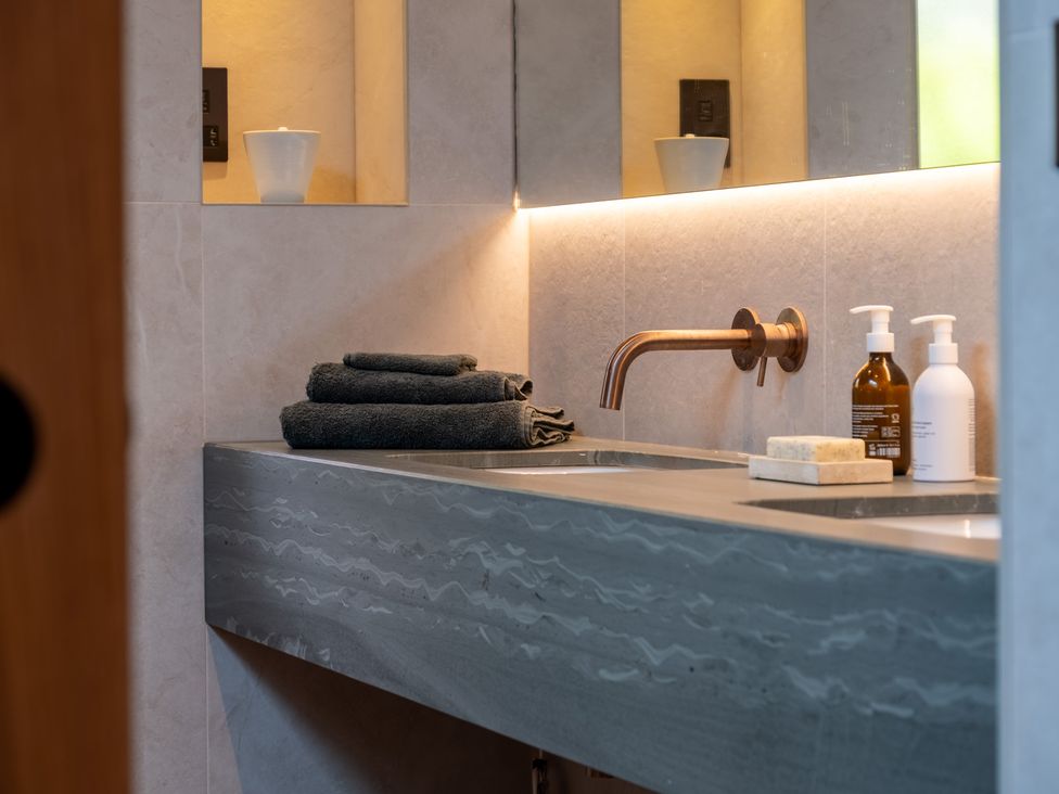 A bathroom sink with towels and bottles at Deer Close in Coniston