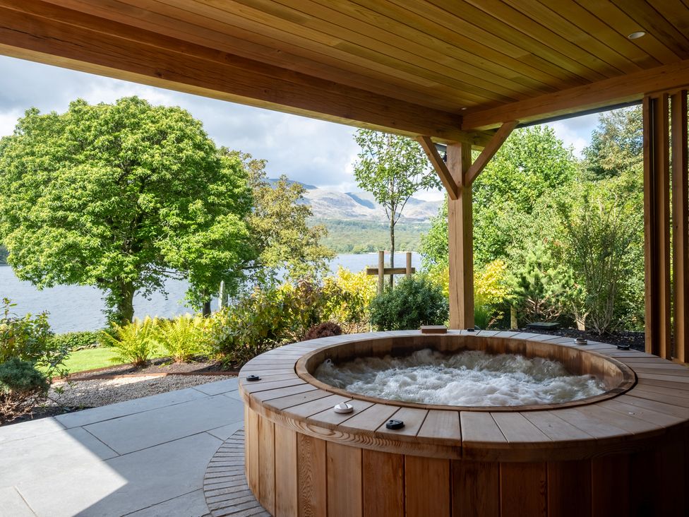 An outdoor area with a hot tub overlooking a lake at Deer Close in Coniston