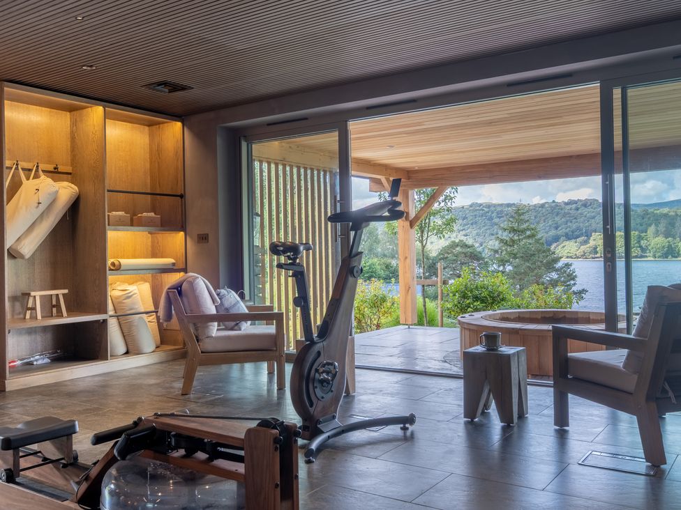 A fitness area with exercise equipment and large windows overlooking a lake at Deer Close in Coniston