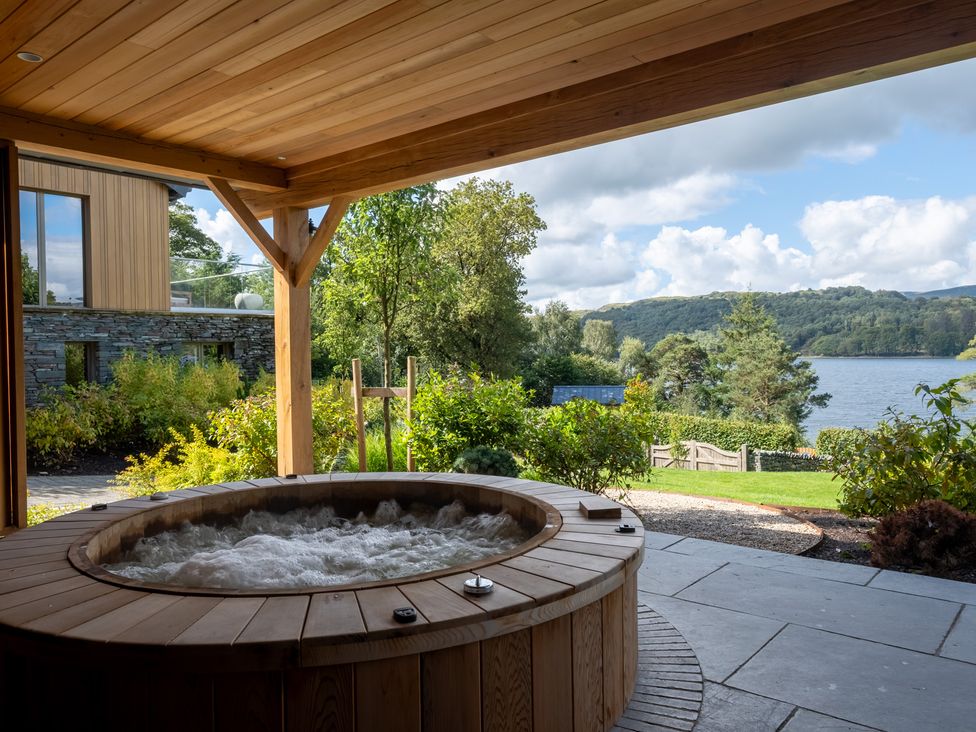 An outdoor area with a hot tub overlooking a lake at Deer Close in Coniston