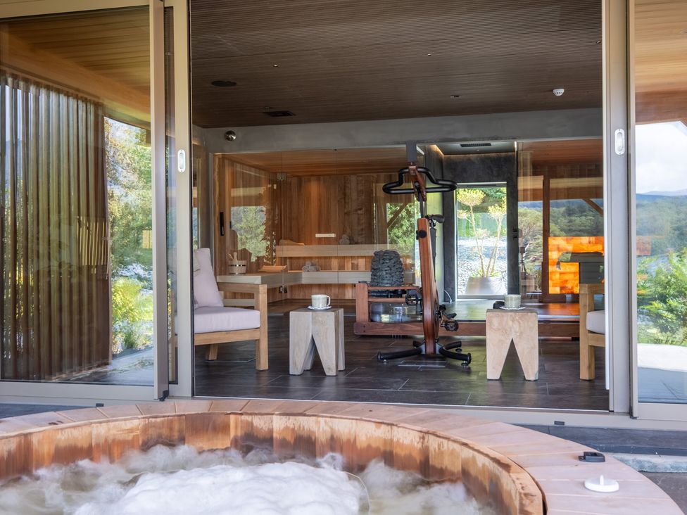 A hot tub with light bubbles and wooden furniture at Deer Close in Coniston