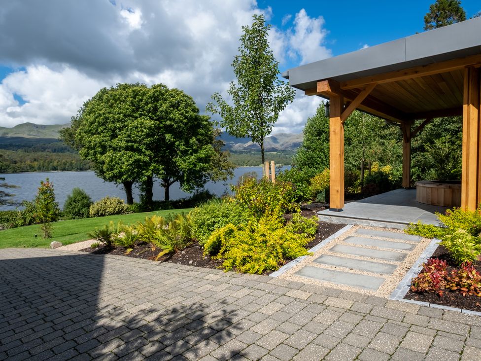 A garden with a pathway and gazebo near a lake at Deer Close in Coniston