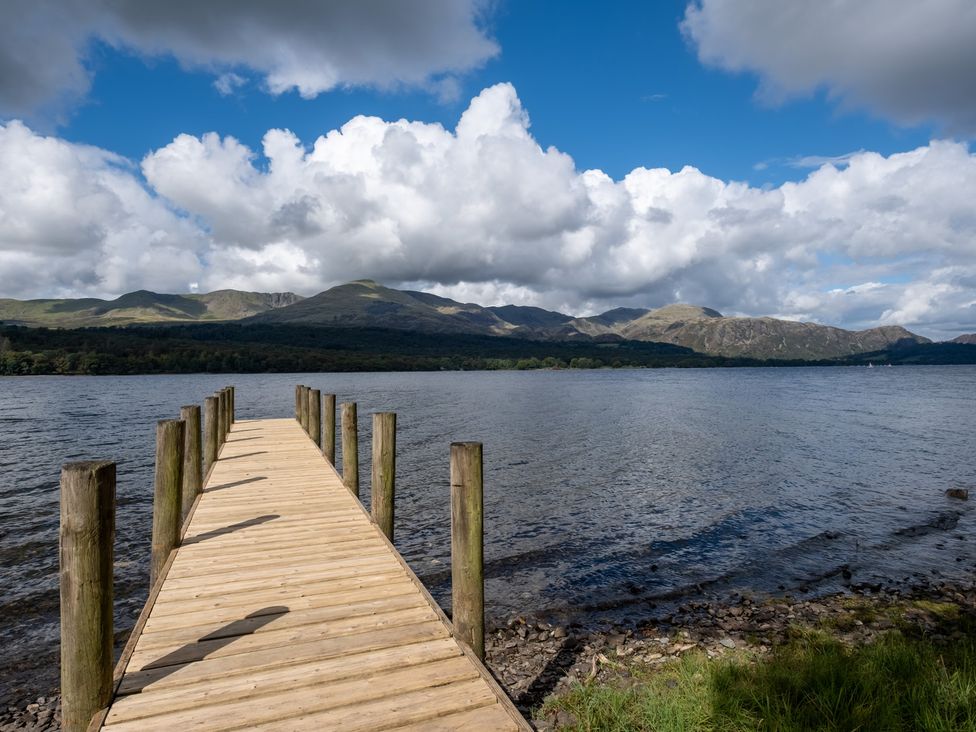 A wooden pier extending over water with mountains in the background at Deer Close in Coniston