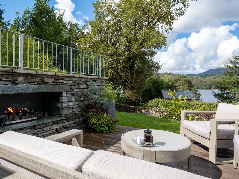 An outdoor patio with a fireplace and seating area at Deer Close in Coniston