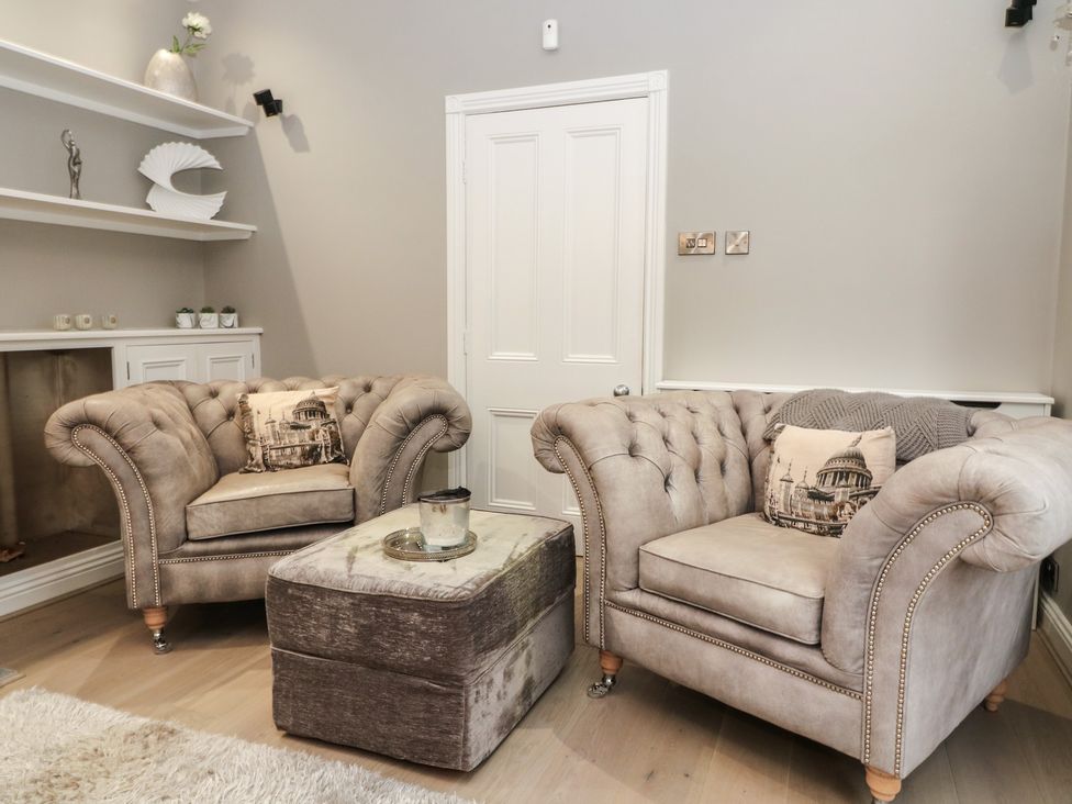A living room with armchairs and an ottoman at Ten Gables in Driffield